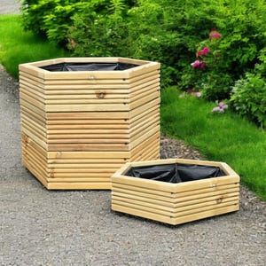 May include: Two hexagonal wooden planters, one large and one small. The planters have a natural wood finish and a black liner. The larger planter is taller than the smaller one. They are set on a grey surface with green foliage in the background.