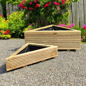 May include: Two triangular wooden planters with a natural finish. The planters have a layered design and are lined with black plastic. They are set on a gravel surface with a backdrop of greenery and a wooden fence.