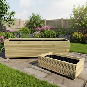 May include: Two rectangular wooden planters with horizontal slat detailing and black interior liners. The planters are constructed from light-coloured wood and feature small feet at the base, designed for outdoor use in a garden setting.