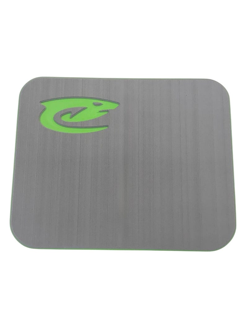 May include: A gray rectangular mat with rounded corners and a green border. The mat features a green stylized shark logo in the upper left corner. The surface has a textured, brushed appearance.