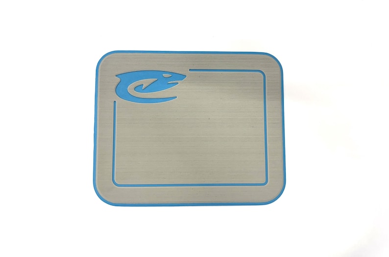 K&ouml;nnte beinhalten: Quadratische Platte aus geb&uuml;rstetem Metall mit hellblauem Rand und passendem Logo in der oberen linken Ecke. Das Logo ist eine stilisierte Wasserlebewesen. Die Platte hat abgerundete Ecken.