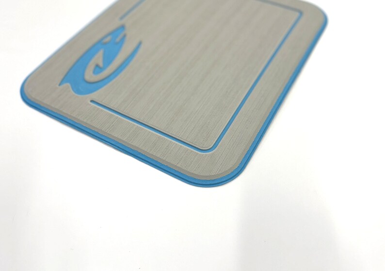 K&ouml;nnte beinhalten: Ein rechteckiges, hellgraues Objekt mit blauem Rand und einem stilisierten blauen Flammendesign in der oberen linken Ecke. Das Objekt hat eine strukturierte Oberfl&auml;che und einen vertieften Innenrand.