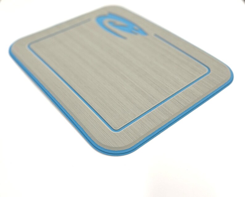 K&ouml;nnte beinhalten: Ein rechteckiges, hellgraues Schneidebrett mit blauem Rand und blauem Logo in der oberen Ecke. Das Brett hat eine Holzmaserung und einen vertieften Innenrand.