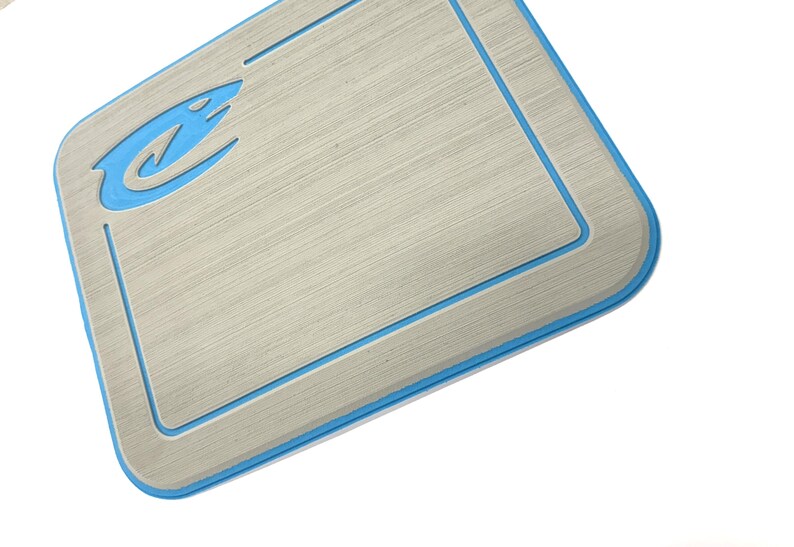 K&ouml;nnte beinhalten: Eine rechteckige, hellgraue Matte mit geb&uuml;rsteter Metalloptik und blauem Rand. Ein blaues Logo befindet sich in der oberen linken Ecke. Die Matte hat abgerundete Ecken und einen vertieften Rand.