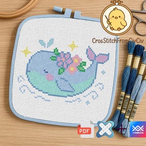 K&ouml;nnte beinhalten: Ein Kreuzstichprojekt mit einem blauen Wal mit Blumenkrone, in einem quadratischen blauen Rahmen. Das Design enth&auml;lt Sterne und blaue Stickgarne. Der Text "CrossStitchFromCivCiv" ist sichtbar.