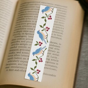 Cross stitch bookmark with blue birds and berries on vintage book, finished embroidery project