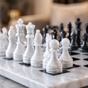 Pu&ograve; includere: Un set di scacchi con pezzi in marmo bianco e nero lucido disposti su una scacchiera in marmo abbinata. Il set include re, regine, alfieri, cavalli, torri e pedoni dettagliati, che mostrano le venature naturali del materiale lapideo.