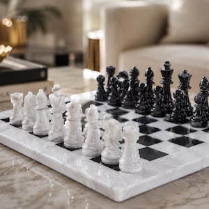 Pu&ograve; includere: Una scacchiera quadrata in marmo bianco e nero con finitura lucida. Il set include una serie completa di pezzi degli scacchi in marmo intagliato in colori coordinati, disposti nelle loro posizioni iniziali sulla superficie a scacchi.
