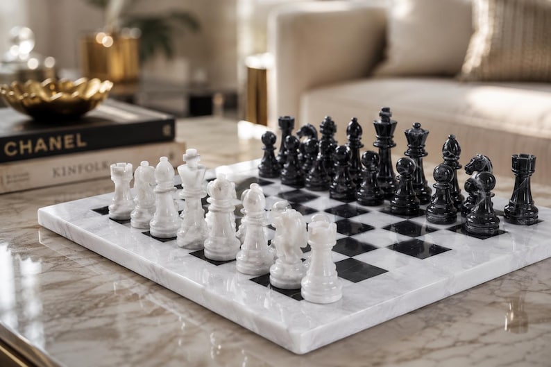Pu&ograve; includere: Una scacchiera quadrata in marmo bianco e nero con finitura lucida. Il set include una serie completa di pezzi degli scacchi in marmo intagliato in colori coordinati, disposti nelle loro posizioni iniziali sulla superficie a scacchi.