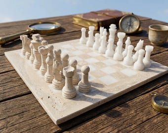 May include: A stone chess set featuring a checkered board with light beige textured stone pieces on one side and smooth white stone pieces on the other. The set includes a king, queen, bishops, knights, rooks, and pawns arranged for play.