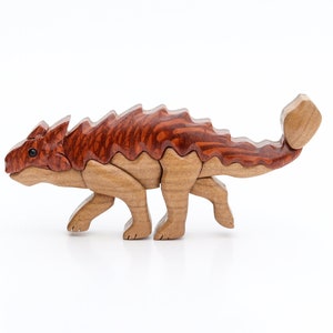 A handmade wooden ankylosaur dinosaur Christmas ornament or magnet made using the segmented wood artform of intarsia.