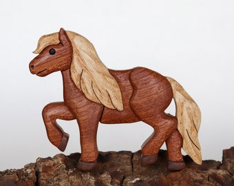 Könnte beinhalten: Eine geschnitzte Holzpferdefigur mit braunem Körper und hellbrauner Mähne und Schweif. Das Pferd steht auf einem Stück Baumrinde.