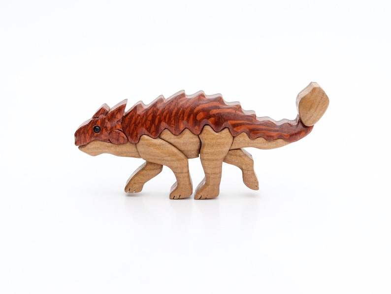 A handmade wooden ankylosaur dinosaur Christmas ornament or magnet made using the segmented wood artform of intarsia.