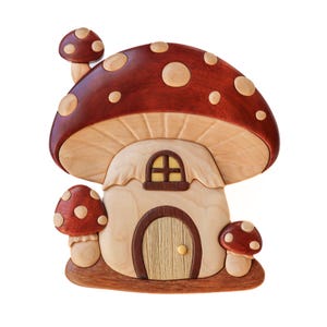 以下が含まれることがあります： 明るい色の円が点在する濃い赤色の帽子が付いた、木製のキノコハウス。家は、小さなアーチ型の窓と木のドアを備えた明るい色のボディをしています。2つの小さなキノコが側面と上部にあります。