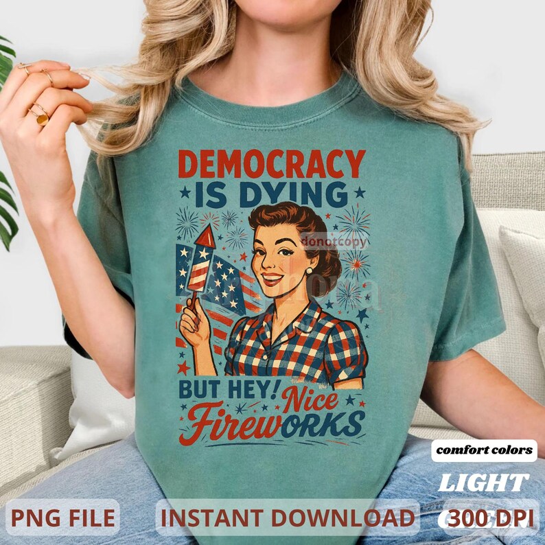 May include: A light green t-shirt with the text "DEMOCRACY IS DYING" and "BUT HEY! Nice Fireworks". The graphic features a vintage illustration of a woman holding a firework and an American flag. The shirt also has the words "comfort colors", "LIGHT", "PNG FILE", "INSTANT DOWNLOAD", and "300 DPI".