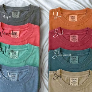 Pode incluir: Uma cole&ccedil;&atilde;o de camisetas Comfort Colors em v&aacute;rias cores, incluindo pimenta, melancia, menta giz, jeans azul, inhame, tijolo, abeto azul e ba&iacute;a. Cada camisa tem gola redonda e uma etiqueta Comfort Colors.