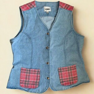 May include: A light blue denim vest with a V-neck and button closure. The vest has red and grey plaid accents on the shoulders and two front pockets. The brand name "GITANO" is visible on the label.