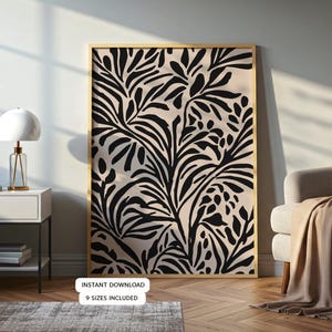 May include: A framed art print featuring a black and beige botanical design. The artwork has a gold frame and is displayed in a room with a lamp, side table, and armchair. The text "INSTANT DOWNLOAD" and "9 SIZES INCLUDED" is visible.