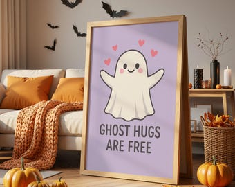 May include: A framed print with a light purple background features a cartoon ghost with outstretched arms and hearts above it. The text "GHOST HUGS ARE FREE" is below the ghost. The frame is light brown. Halloween decor.