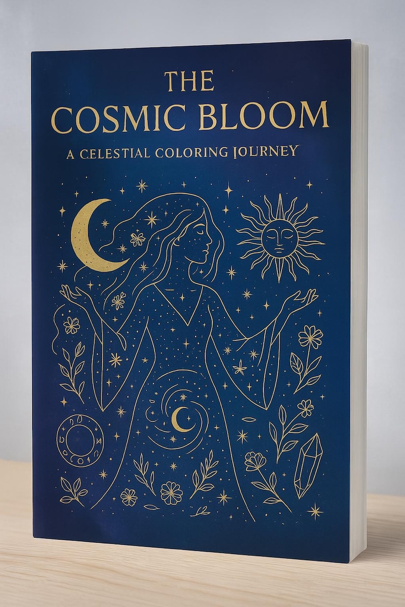 Puede incluir: Un libro de tapa dura titulado "The Cosmic Bloom: A Celestial Coloring Journey". La portada es azul marino con ilustraciones doradas de una mujer, la luna, el sol, estrellas y elementos florales. El libro est&aacute; de pie.