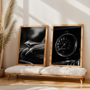 May include: Two framed black and white prints of vintage car details. One features a hood ornament, the other a speedometer. The prints are displayed on a wooden bench with white cushions, next to a potted plant.