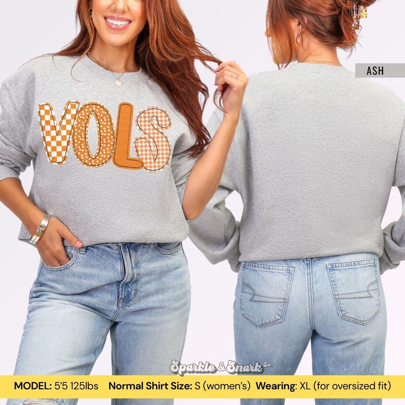 May include: A light gray sweatshirt with the word "VOLS" in orange and checkered patterns. The sweatshirt is shown from the front and back, with the word "ASH" visible on the back. The model is wearing an XL for an oversized fit.