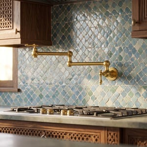 May include: A wall-mounted brass pot filler tap with a double-jointed swing arm, positioned above a stainless steel gas hob. The tap features a metallic gold finish and is set against a backsplash of blue and green patterned tiles.