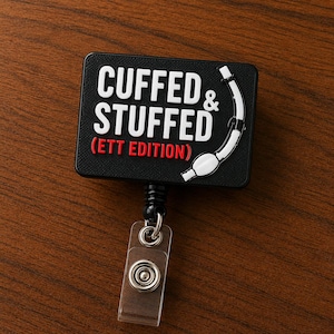 May include: A black rectangular badge reel featuring the white text CUFFED & STUFFED and the red text (ETT EDITION). A white graphic of an endotracheal tube is positioned on the right side. The badge reel includes a clear plastic strap with a metal snap.