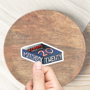 Op de afbeelding: Een blauwe en witte sticker met een tekening van een luciferdoosje met de tekst "Matchbox Twenty" en het nummer "20" erop.