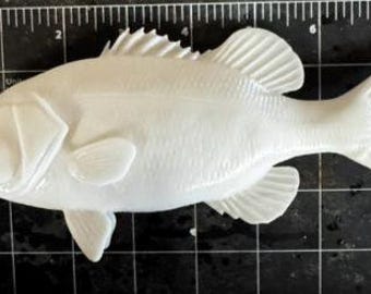 Könnte beinhalten: Eine massive weiße Fischfigur auf einer schwarzen Schneidematte mit Raster. Der Fisch misst etwa 18 cm in der Länge von der Maulspitze bis zur Schwanzflosse und zeigt detaillierte Schuppen, Flossen sowie eine ausgeprägte Kiemenstruktur.
