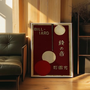 Puede incluir: Un póster enmarcado con fondo burdeos y círculos blancos. El póster tiene la palabra "BILLIARD" en la parte superior y texto y símbolos japoneses. El póster está en una habitación con un sofá de cuero verde y una pared de madera.