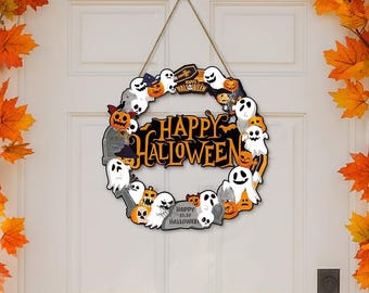 Może przedstawiać: Wieniec na Halloween o okrągłym kształcie, z duchami, dyniami i napisem "Happy Halloween". Wieniec zawieszony jest na sznurku i umieszczony na białych drzwiach, z pomarańczowymi jesiennymi liśćmi w tle.