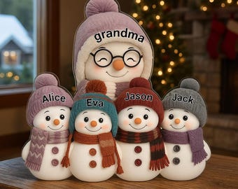May include: A family of snowman figurines, each with a unique hat and scarf. The largest snowman is labeled "grandma" and wears glasses. The smaller snowmen are named Alice, Eva, Jason, and Jack. The snowmen are on a wooden surface.