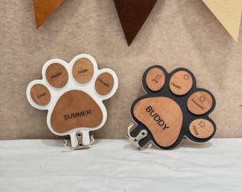 May include: Two paw-shaped wooden wall hooks. One is white with brown accents and the name "SUMMER". The other is black with brown accents and the name "BUDDY". Each has small hooks for hanging items. The words "Love", "Health", "Hope", and "Growth" are on the white paw.