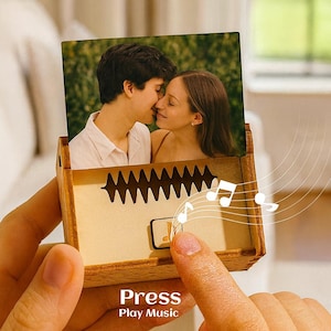 May include: A wooden music box featuring a photograph of a couple. The box has a sound wave design and the words "Press Play Music" printed on the bottom. Musical notes are illustrated around the box.