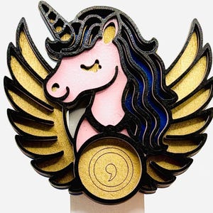 May include: A layered wooden unicorn with gold wings, a pink face, and blue hair. The unicorn has a black horn and is surrounded by a black outline. The wings are gold with black outlines. The unicorn is a whimsical, decorative item.