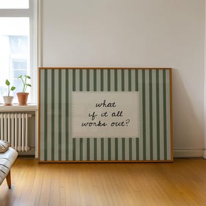 May include: A framed artwork with a green and white striped background and a central rectangular panel. The panel features the text "what if it all works out?" in a handwritten style. The frame is a warm brown colour.