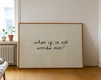 May include: Large framed artwork with the text "what if it all works out?" in a handwritten style. The frame is a warm brown color, and the background is a cream color. The artwork is displayed in a room with hardwood floors and a window.