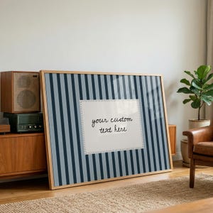 Pu&ograve; includere: Una grande stampa rettangolare incorniciata con un motivo a righe verticali nei toni del blu scuro e del grigio chiaro. Al centro, un riquadro bianco con bordo cucito mostra il testo scritto a mano in nero, your custom text here.