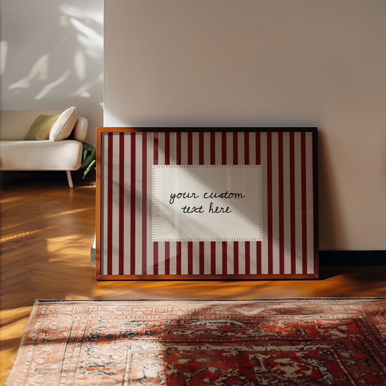 Pu&ograve; includere: Una stampa rettangolare incorniciata con un motivo a strisce verticali rosso scuro e bianche. Al centro, un'etichetta rettangolare bianca con bordo cucito contiene il testo scritto a mano in nero, your custom text here.
