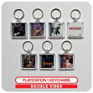 May include: A collection of seven double-sided PlayStation 1 keychains. Each keychain features a different game cover, including titles like "Metal Gear" and "Final Fantasy VII". The keychains have a clear, square design with a silver keyring.