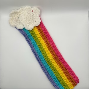 May include: A handmade crochet rainbow with a white cloud at the top. The rainbow features stripes of purple, blue, green, yellow, orange, and pink. The craft item is made of yarn.
