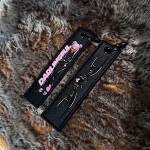 May include: Two black keychains with a cartoon graphic and the word "DARLINGFUL" in pink. One keychain features a pink-haired character, and the other has a white design. Both have a black ring.