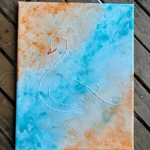 White embroidery swan on blue and orange painted canvas