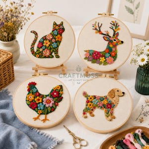 Può includere: Quattro telai da ricamo circolari su supporti in legno, ognuno con uno sfondo in tessuto color crema. I disegni includono un gatto, un cervo, una gallina e un cane, tutti riempiti con motivi floreali colorati a petali vari, nei toni del rosso, blu e giallo.