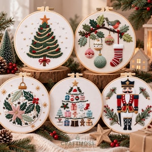 May include: Five circular embroidery hoops featuring Christmas designs on white fabric. The designs include a green Christmas tree, a bird with ornaments and a stocking, a poinsettia, a tree made of gifts, and a nutcracker soldier figure.