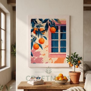 May include: A framed artwork depicts a window with blue panes and a pink frame, with orange fruit and green leaves. A small potted orange tree sits on a wooden table, along with a bowl of oranges and a stack of books.