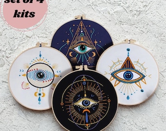 May include: Set of four embroidery kits featuring eye designs. Each kit includes a circular hoop with a fabric canvas displaying an embroidered eye in various colors, including blue, gold, and white. The text "set of 4 kits" is in a pink circle.