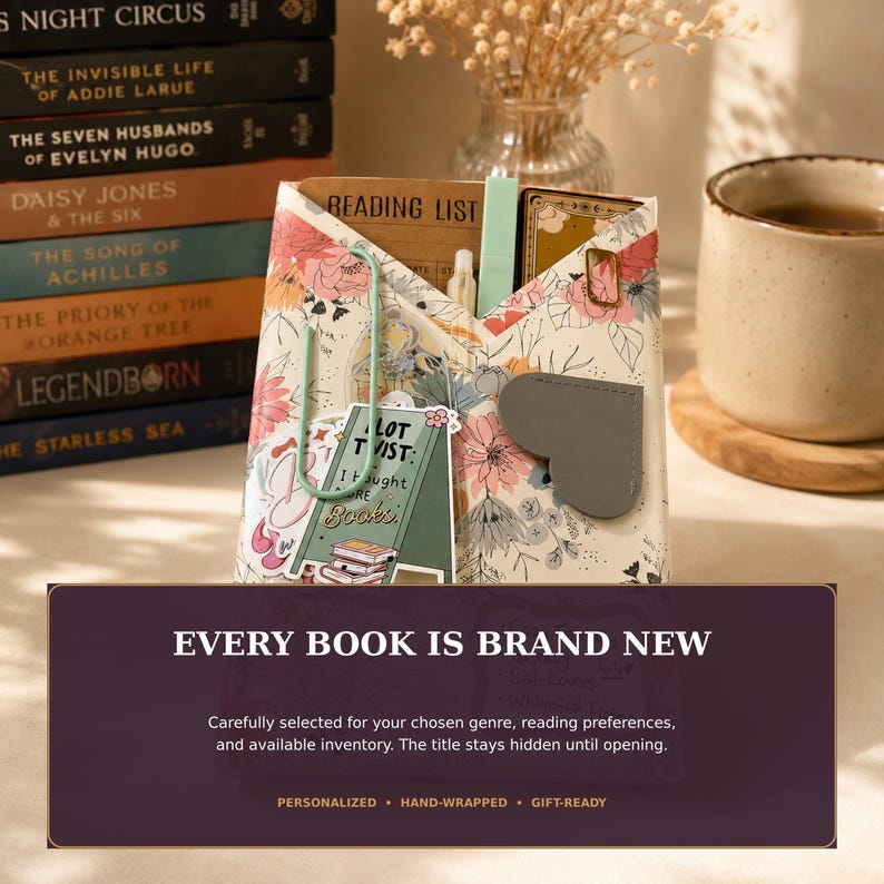 May include: A floral patterned paper envelope containing a reading list, a sticker with the text A LOT TWIST I bought more Books, a light green paperclip, and a grey heart-shaped bookmark, positioned near a stack of books and a ceramic mug.