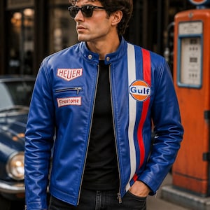 Peut inclure: Une veste de course en cuir bleu avec un col montant, une fermeture éclair frontale et des manches longues. La poitrine présente un écusson blanc Heuer et un écusson rouge Firestone. Une bande verticale blanche et rouge orne le côté gauche.